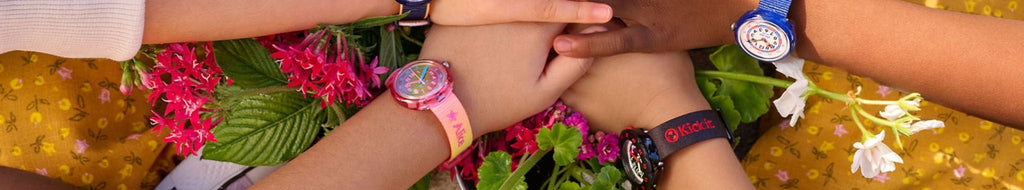 Four childrens hands each with Flik-Flak watch on wrist 