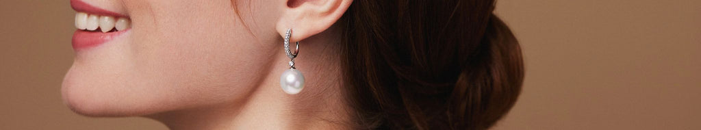 Side profile of woman smiling lifting head slightly with pearl drop earring 