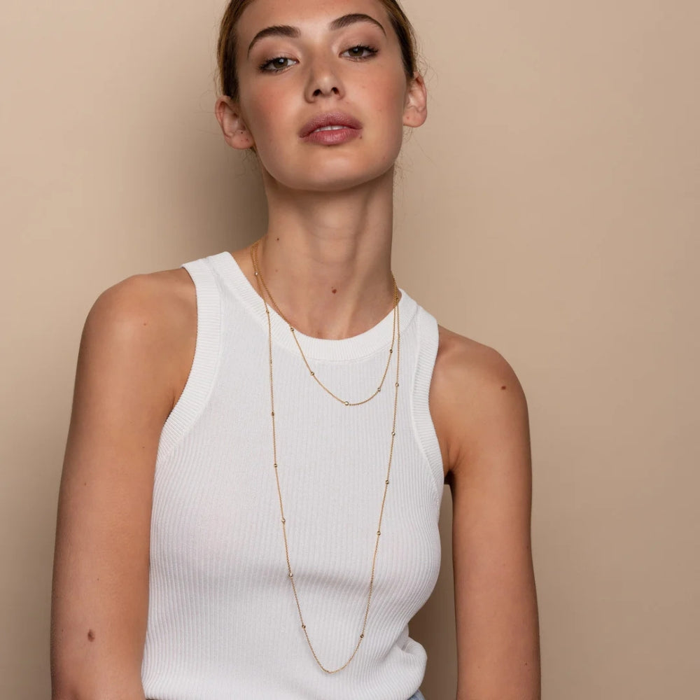 Woman wearing a long necklace against a beige background