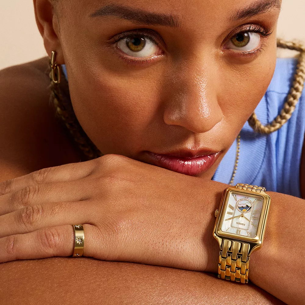 Woman wearing a gold watch with a close-up of her face and hand.