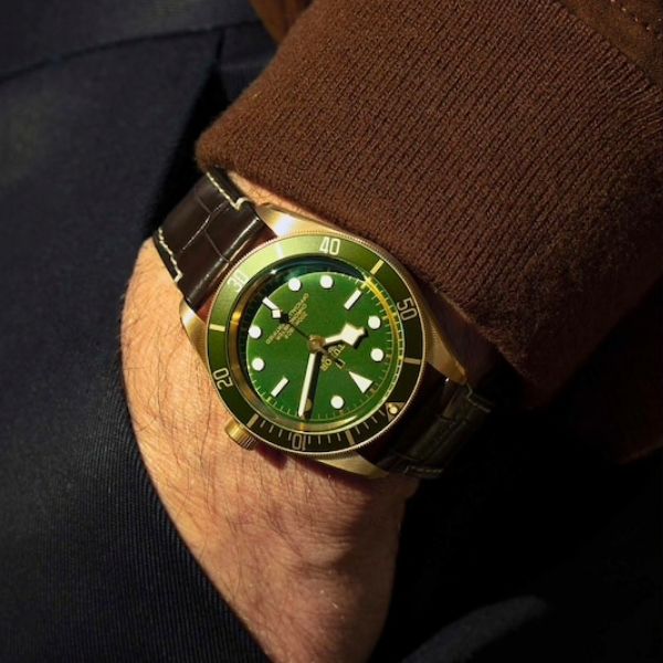 A person wearing a green dial Black Bay Fifty-Eight TUDOR watch