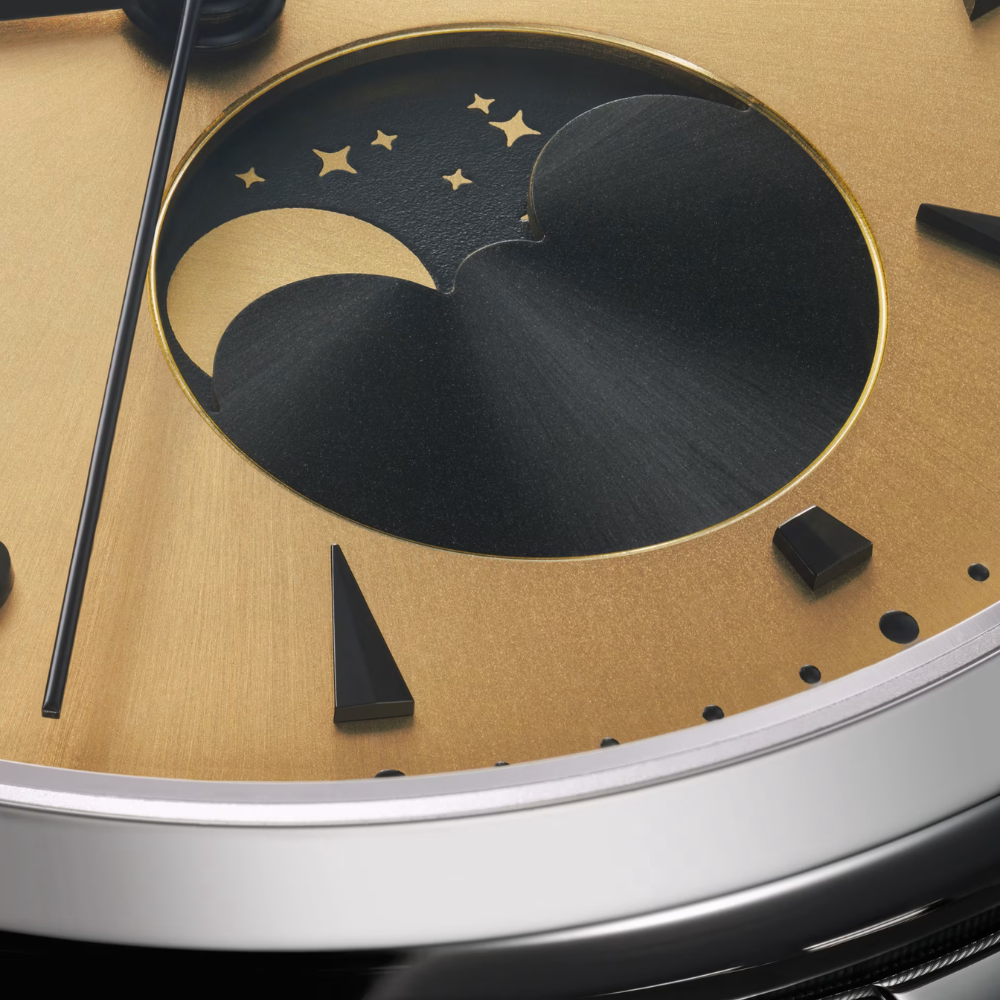 Close-up of a watch face with moon and stars (moonphase), and hour hand on a gold background