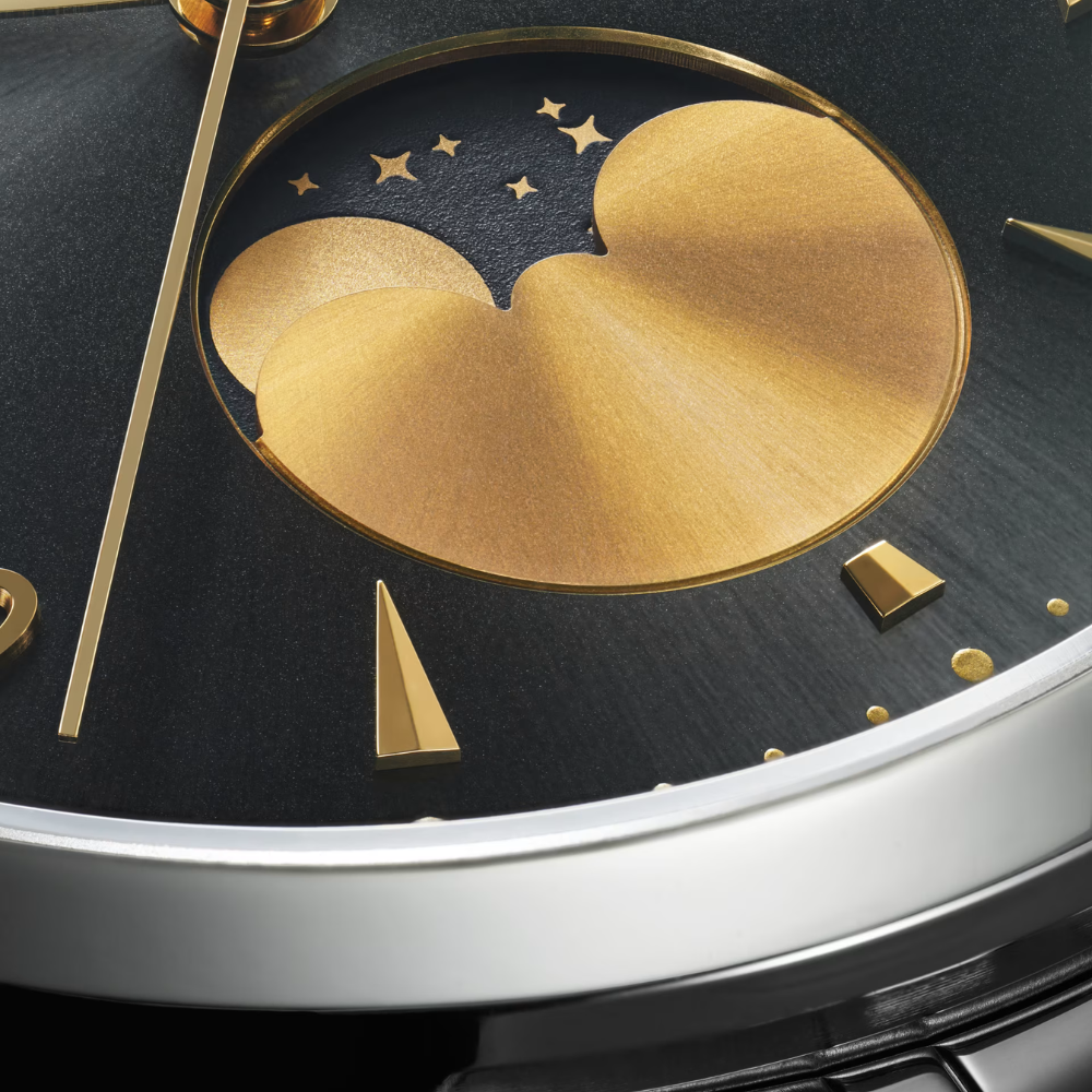 Close-up of a watch face with a gold clouds design, with stars and a moon (moonphase), on a dark background