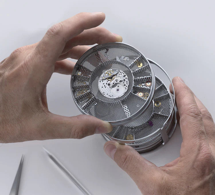 Hands holding a stack of small Rolex pieces
