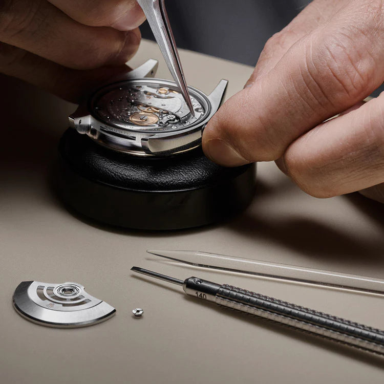 A person's hands working on a Rolex watch